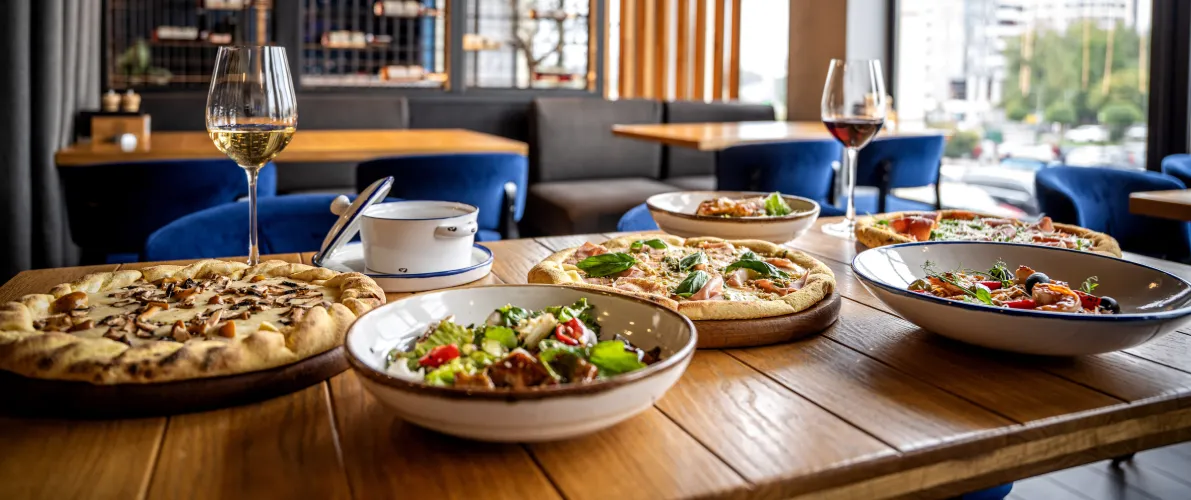 Table avec pizzas, pâtes et verres de vin